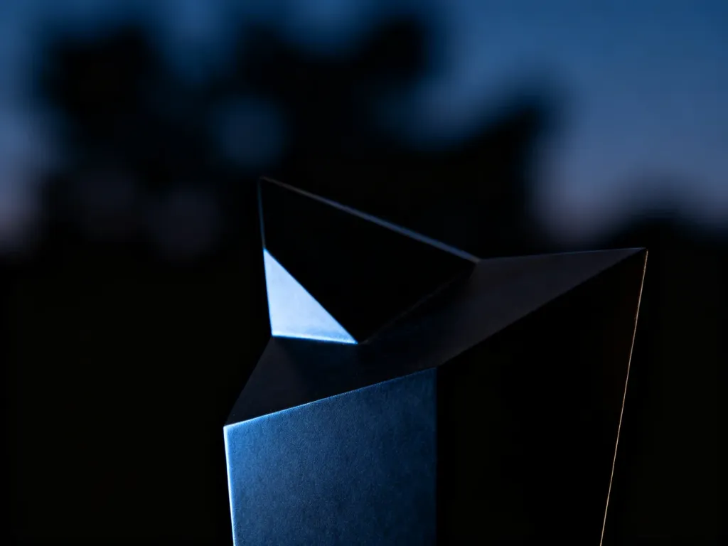 Minimalistyczna geometryczna rzeźba w odcieniach głębokiego grafitu i granatu, podkreślająca estetykę stylu dark.